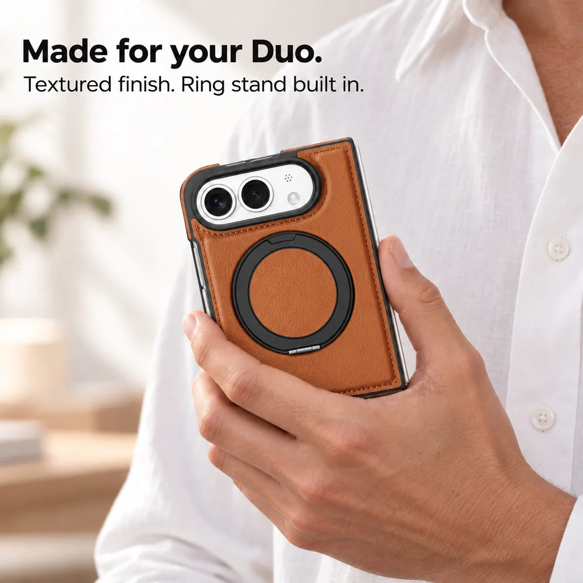 Hand holding a textured synthetic leather folding phone case with the ring stand folded flat. #color_Saddle Brown
